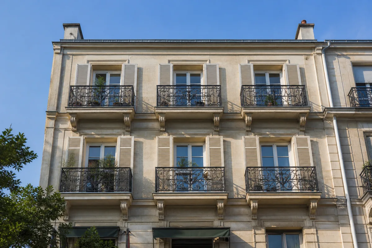 Façade d’immeuble résidentiel en pierre claire avec balcons en ferronnerie